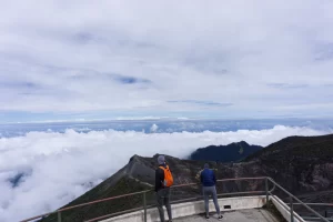 Mountain landscape with people on an observation deck overlooking a sea of clouds.